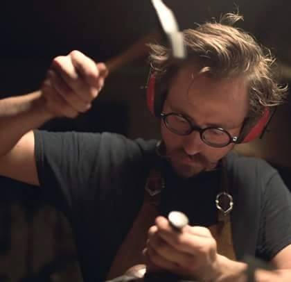 A man with headphones on holding a knife.