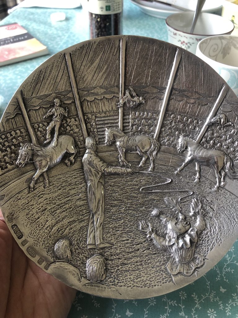 metal plate with carvings of a scene in a circus