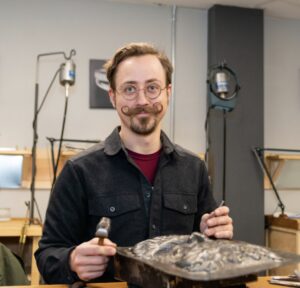 A man holding a spoon and smiling at the camera.