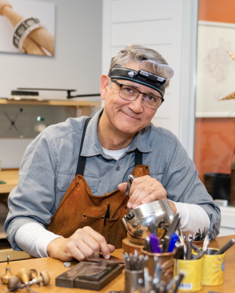 A man wearing an apron and glasses is making something