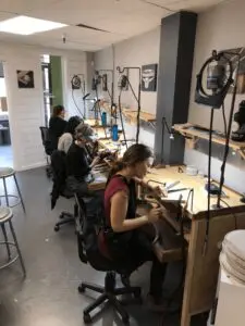 A group of people sitting at tables working on electronics.