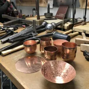 A table with many copper cups and bowls on it