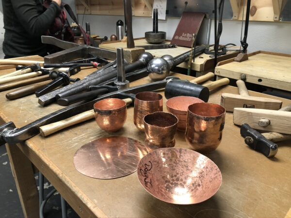 A table with many copper cups and bowls on it