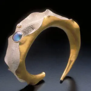 A gold and silver bracelet with a blue stone.